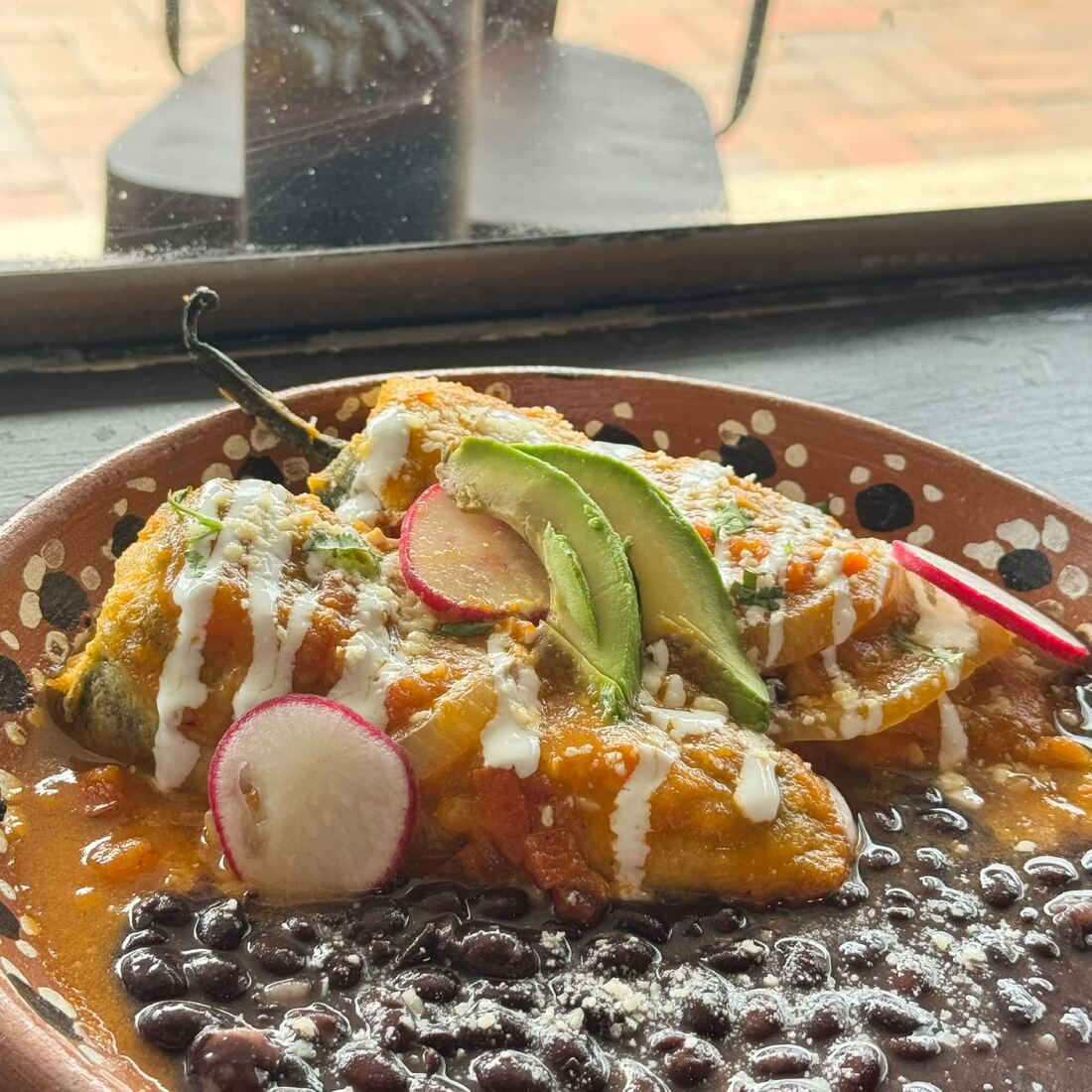 Oaxaca cheese stuffed poblano peppers under salsa ranchera with cr&egrave;me fra&icirc;che and black beans